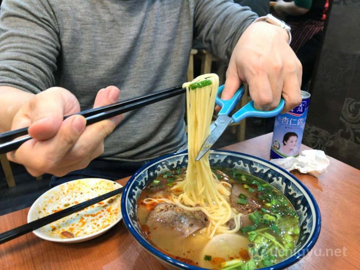 火焰山の蘭州ラーメンをハサミで切る